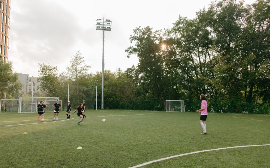 Coach guiding players through a training drill on a sunny field