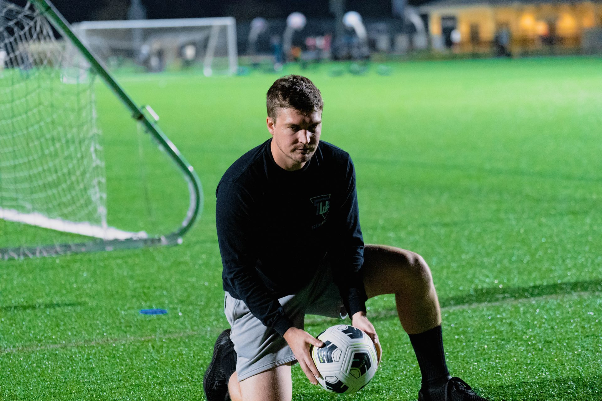 Coach Austin Mills setting up a night training session on a floodlit field